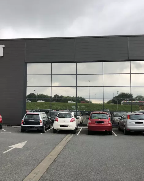 Bâtiment avec grande vitrine et voitures garées devant